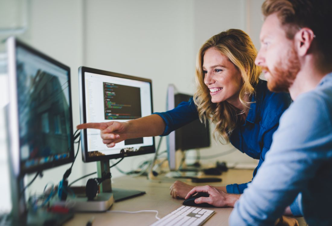 Mobile app developers considering how they should develop their luxury app by looking at mockups on a desktop with code on another screen.